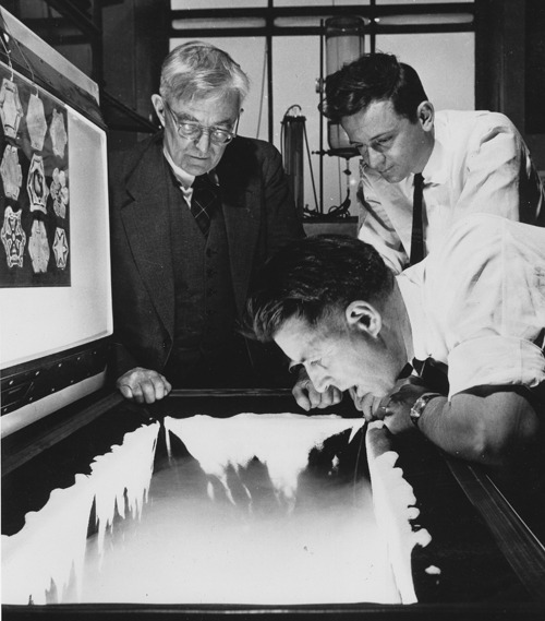 Nobel Prize winner Irving Langmuir is standing next to  Bernard Vonnegut (Kurt Vonnegut’s brother) in a GE lab. Vincent Schaefer is leaning over a cold chamber where they are seeding a snow cloud. Image credit: The Schenectady Museum of Innovation and Science.